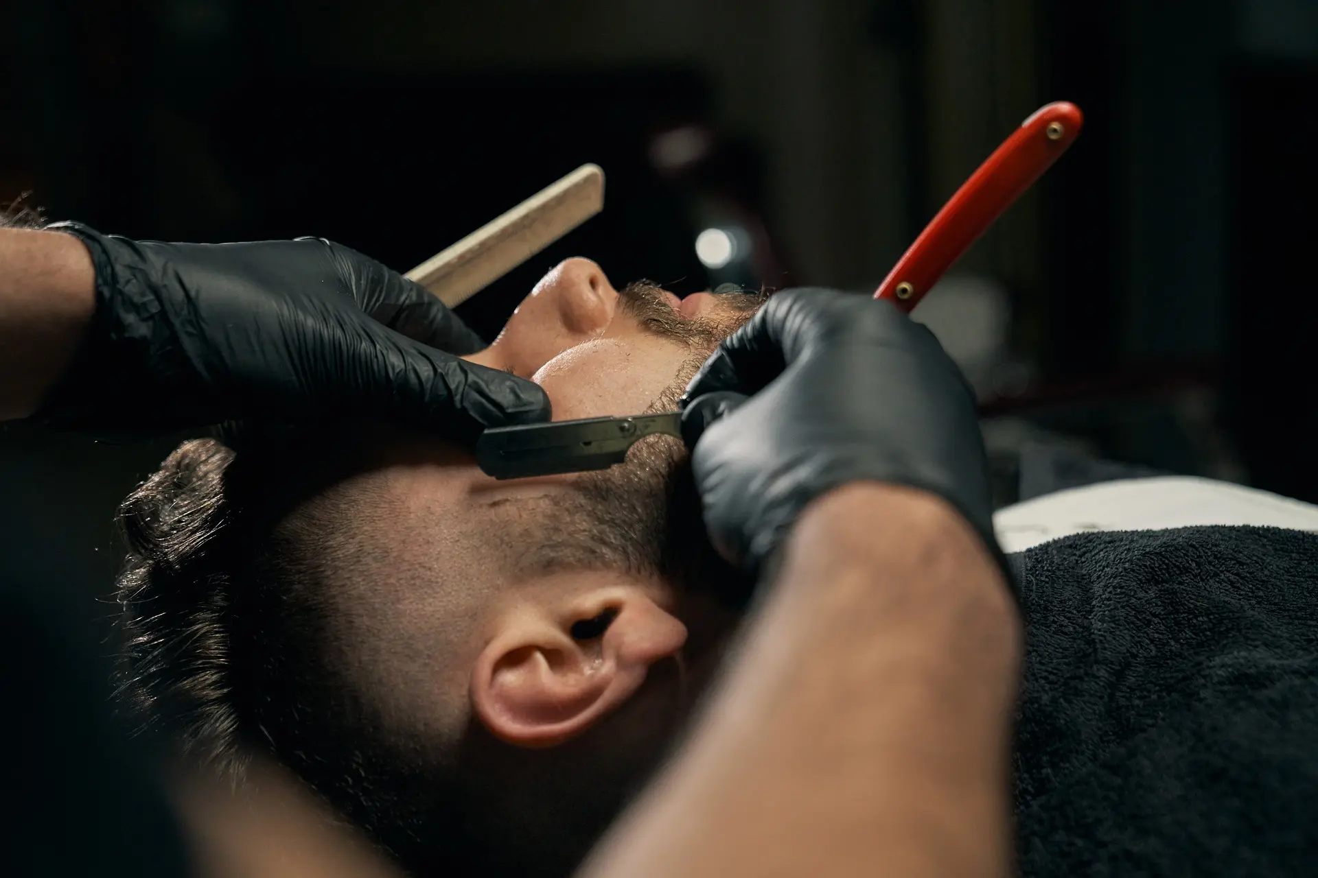 Professional barber giving a beard trim to a client in a salon